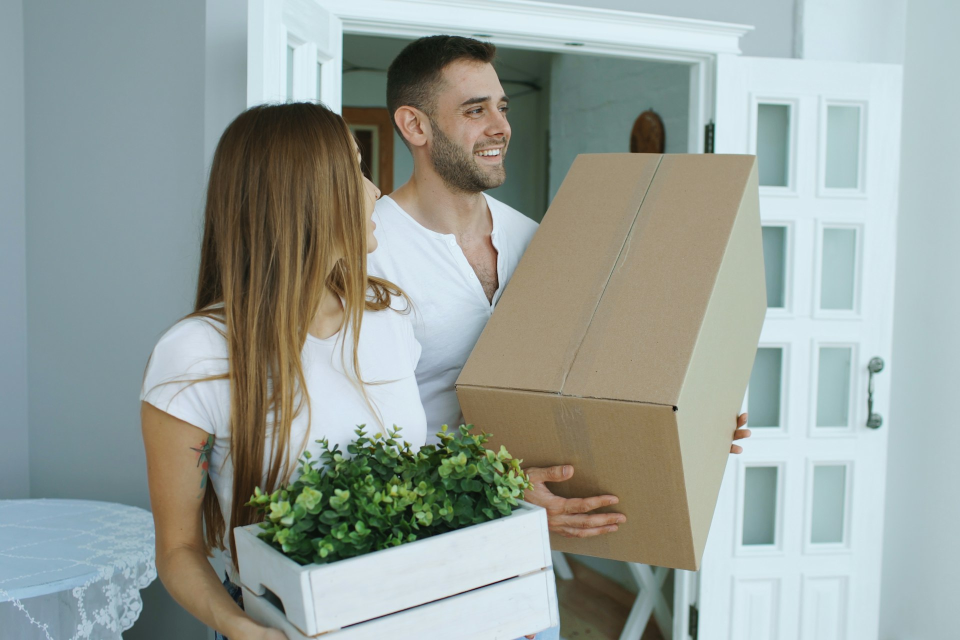 Couple carrying moving boxes through the doorway of their next Utah home