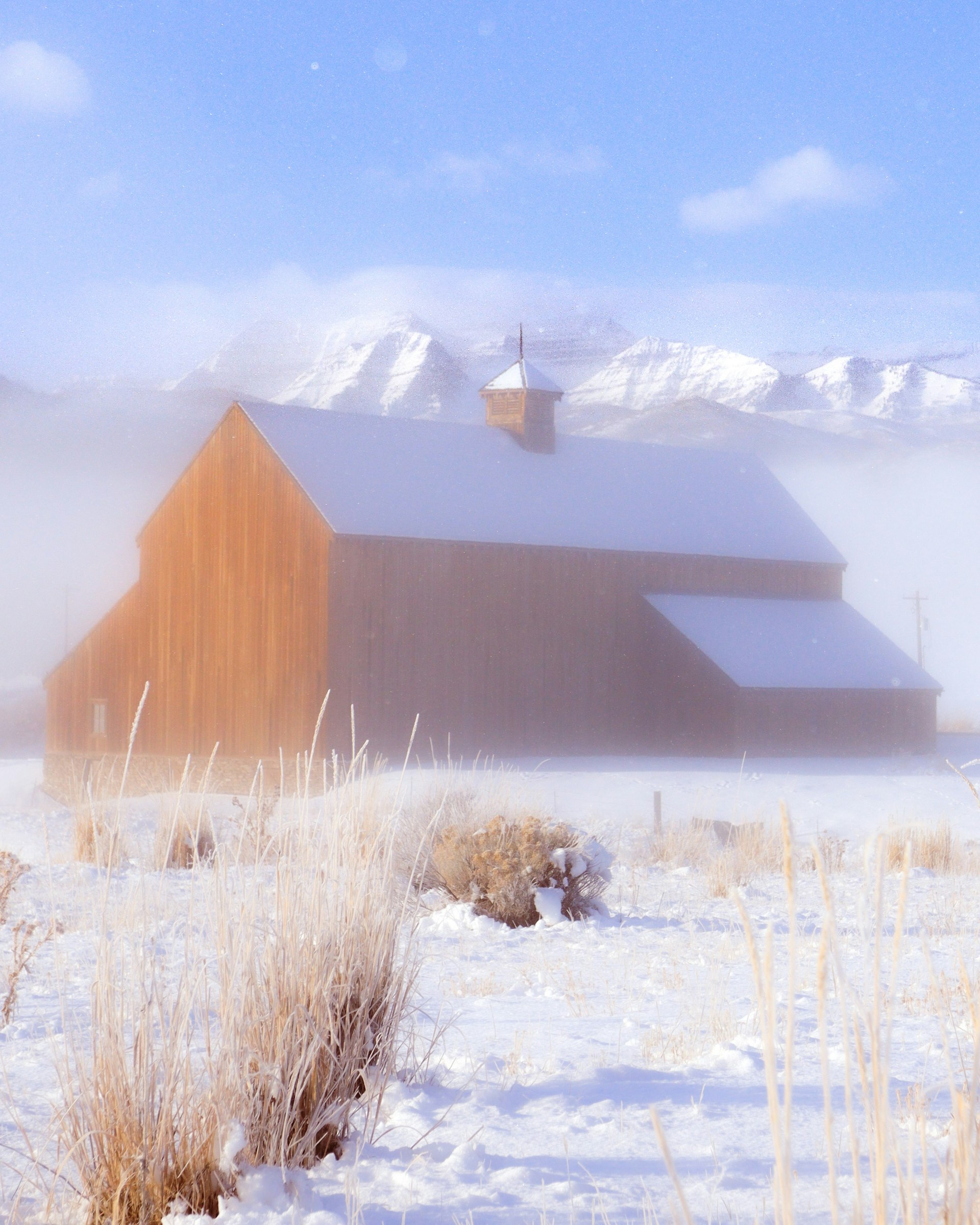 Snowy wooden barn in Heber Valley with the Wasatch mountains beyond